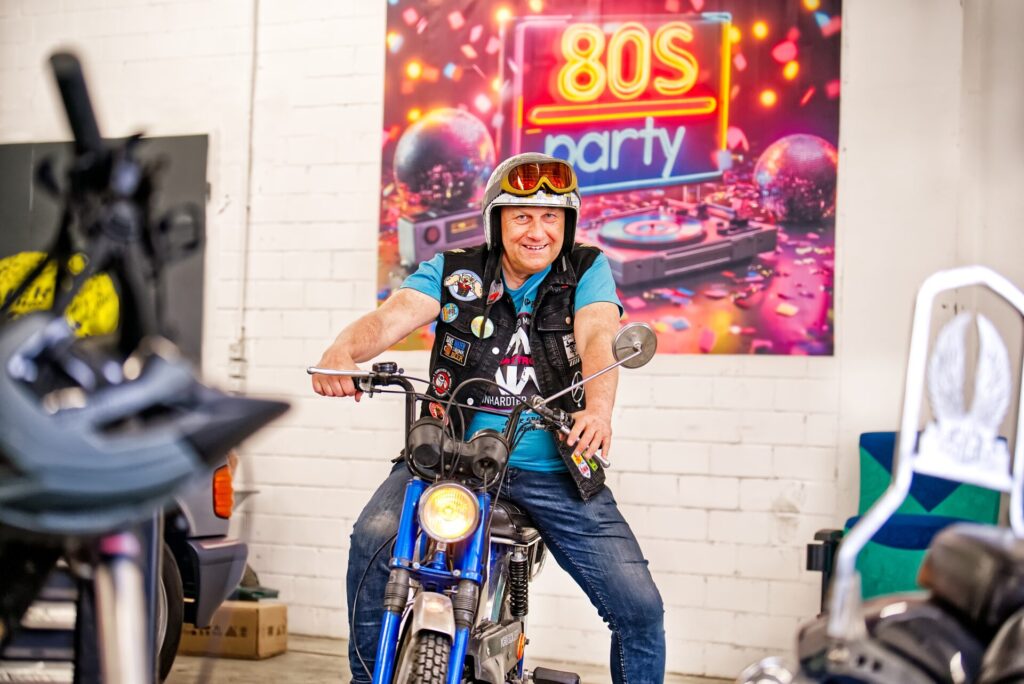 Ralf Oppenländer mit seinem Discokugelhelm. Er passt gut zur Schrauber- und Partylocation der Muneros. Auch das Moped, die Kreidler Flory, ist Baujahr 1984 und damit typisch 80er-Style.